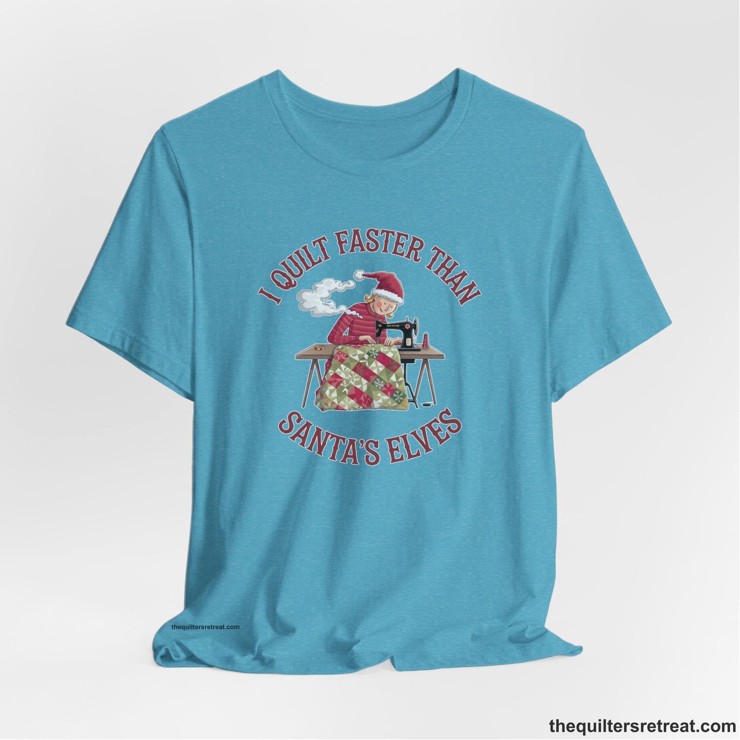 A Heather Aqua Short Sleeve T-Shirt with a whimsical illustration of a quilting woman with "I Quilt Faster Than Santa's Elves" text
