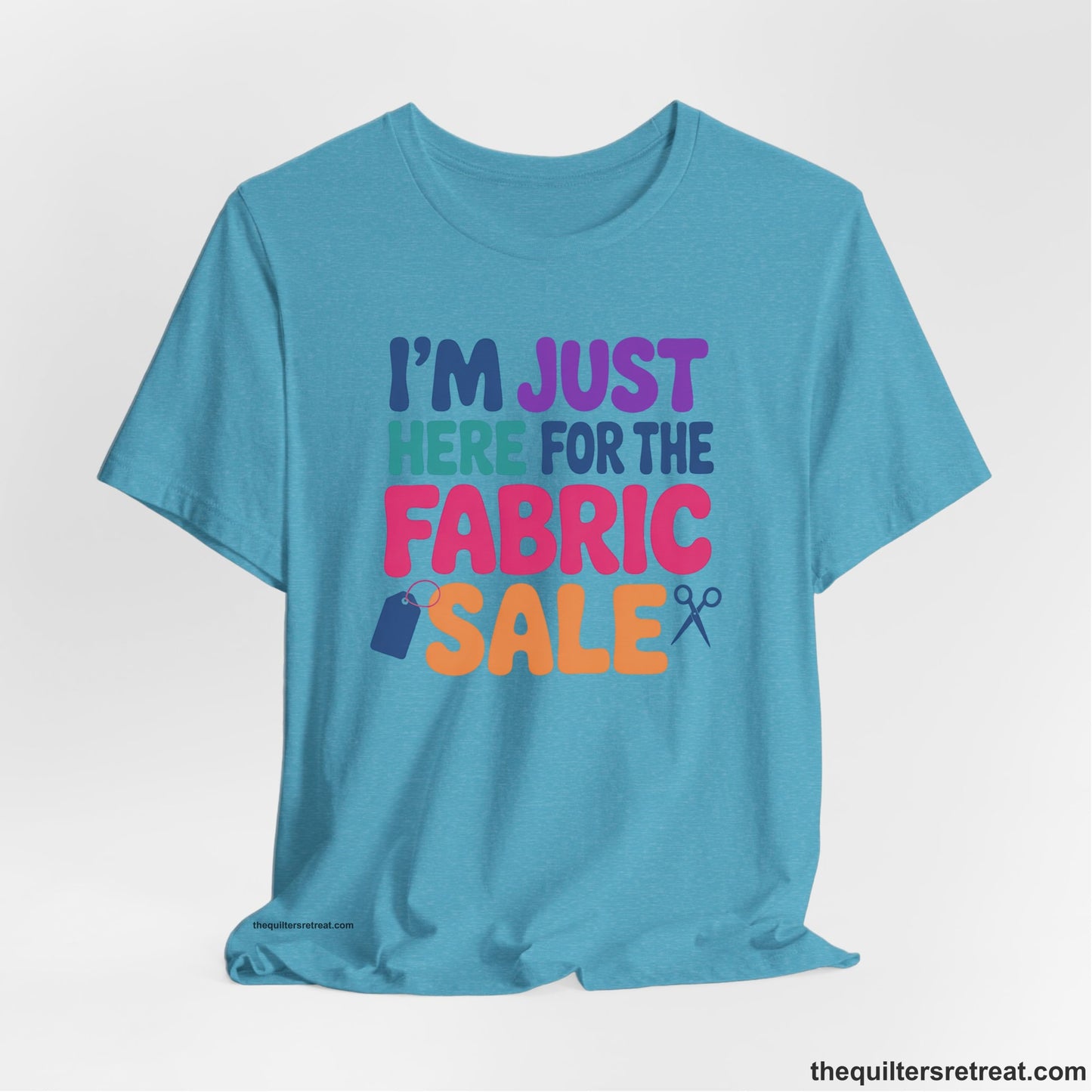 A Heather Aqua Short Sleeve T-Shirt with a playful "I'm Just Here for the Fabric Sale" text with colorful letters and sewing icons