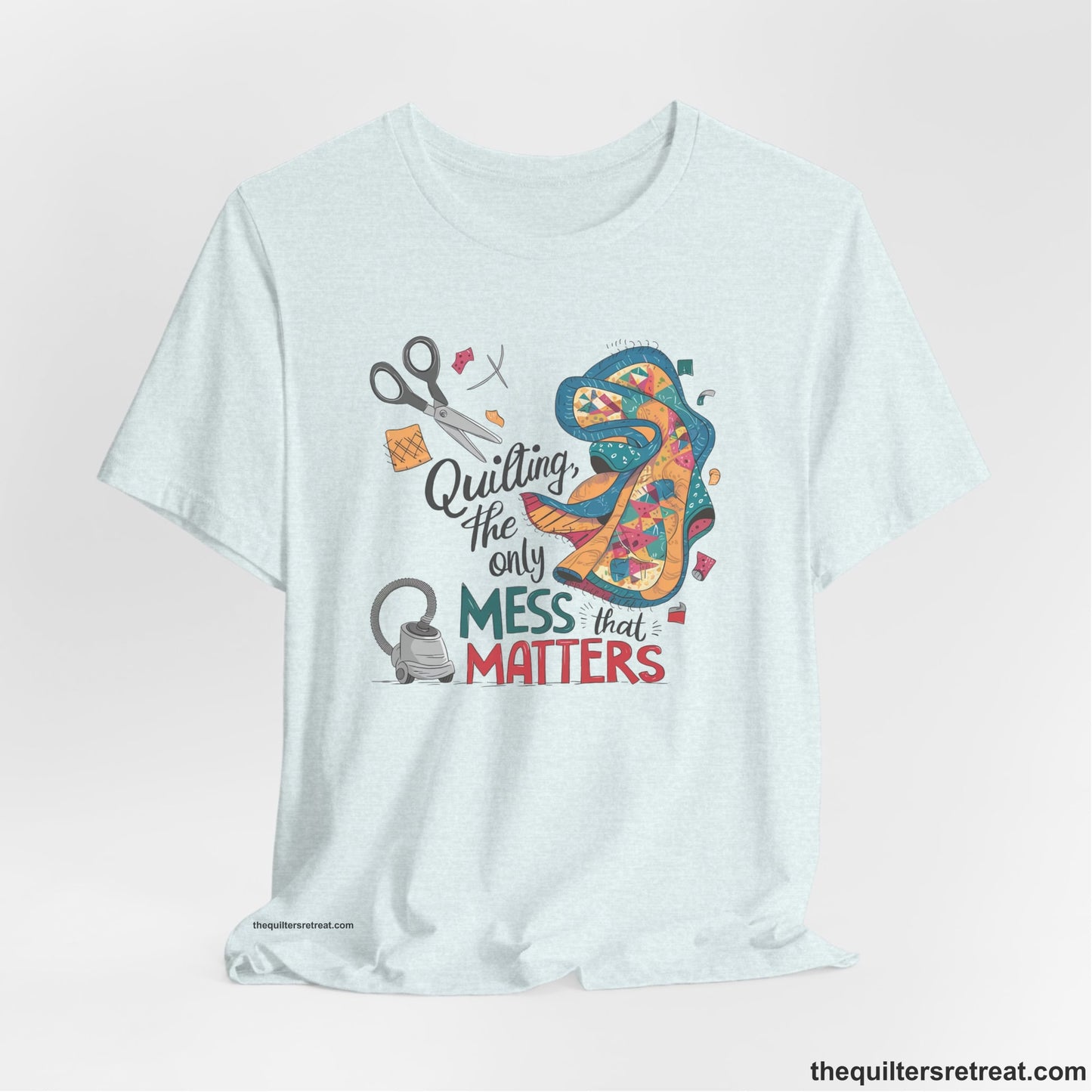 A Heather Ice Blue Short Sleeve T-Shirt with a quilting tools and patchwork pieces with bold "Quilting, the only mess that matters" text