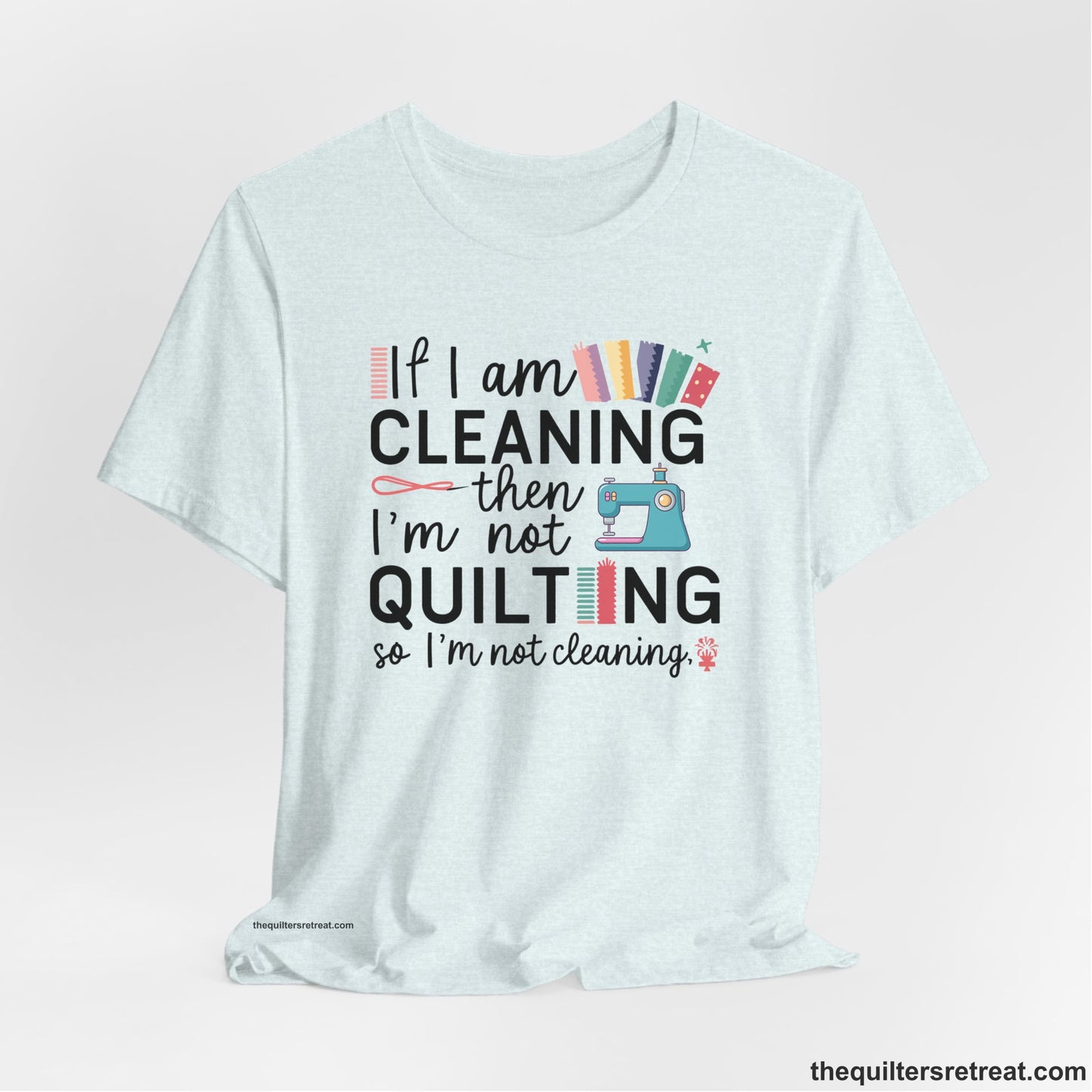 A Heather Ice Blue Short Sleeve T-Shirt with a If I am cleaning then I'm not quilting text with sewing machine and fabric graphics