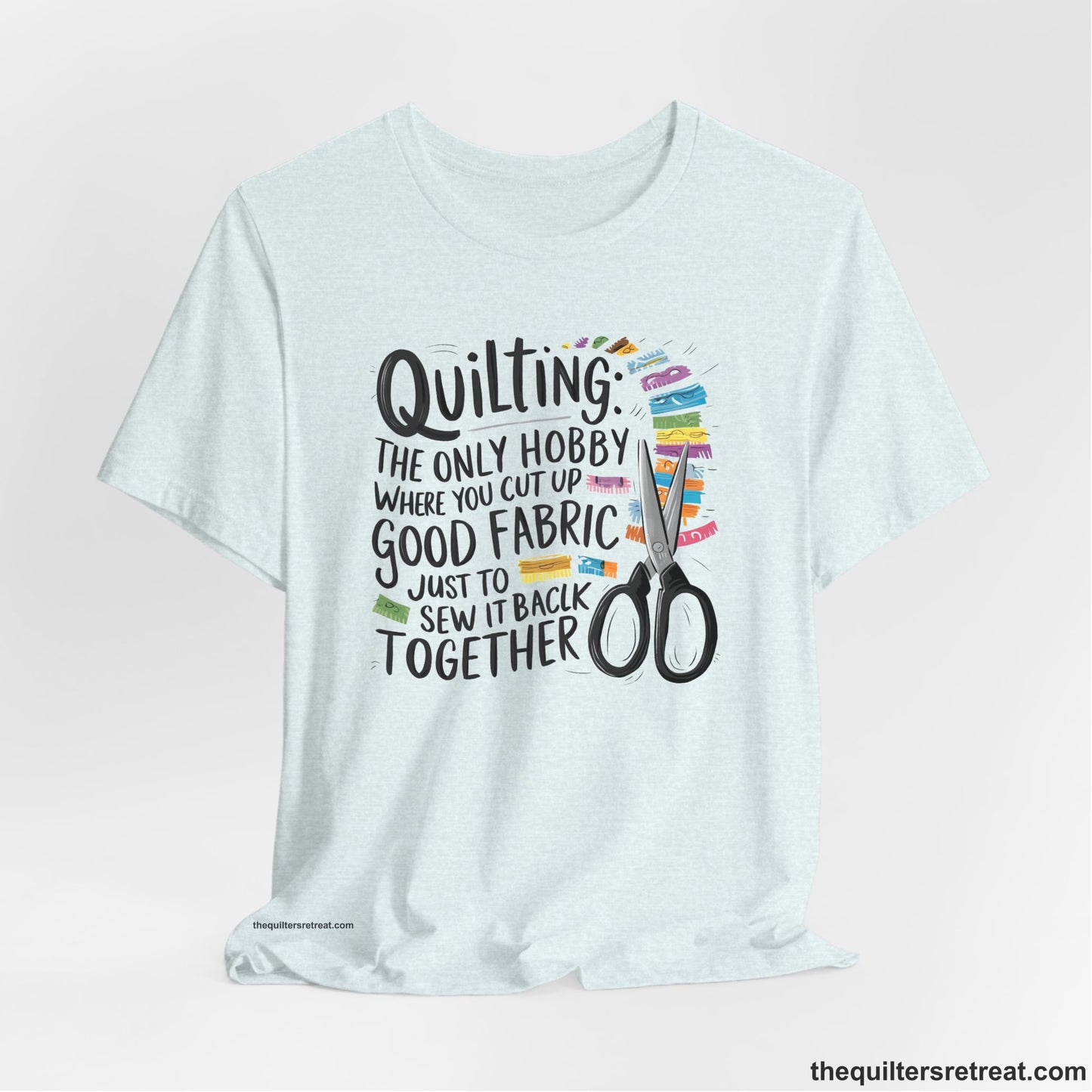 A Heather Ice Blue Short Sleeve T-Shirt with a quilting-themed text with colorful fabric pieces and scissors in a whimsical style