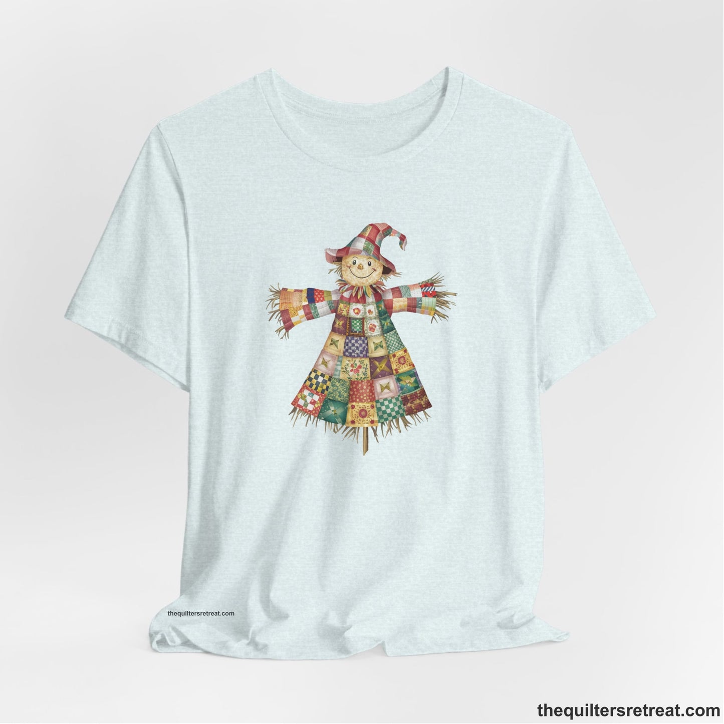 A Heather Ice Blue Short Sleeve T-Shirt with a patchwork scarecrow with a cheerful face in a whimsical style