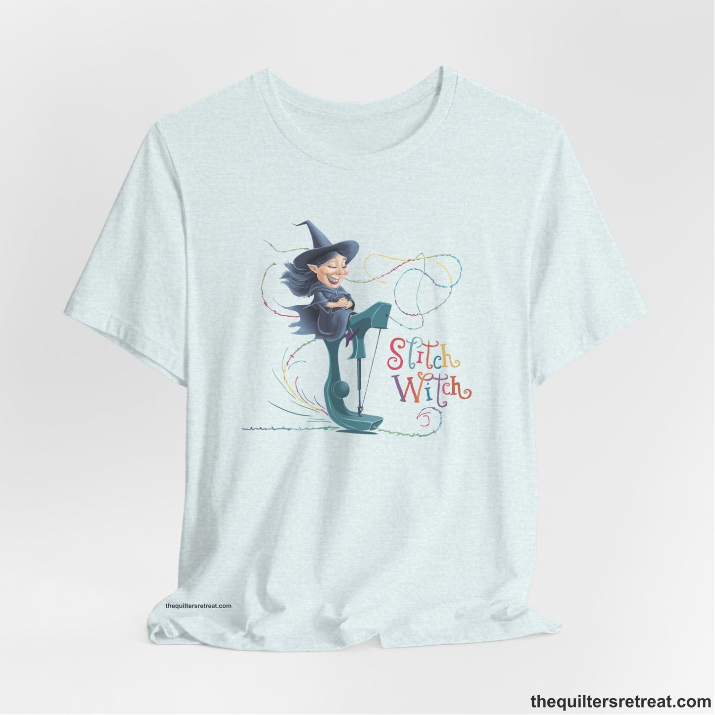 A Heather Ice Blue Short Sleeve T-Shirt with a witch on vintage sewing machine with "Stitch Witch" text in playful, colorful style