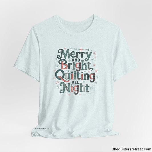 A Heather Ice Blue Short Sleeve T-Shirt with a Merry and Bright Quilting All Night text with festive patterns and stars in a whimsical style