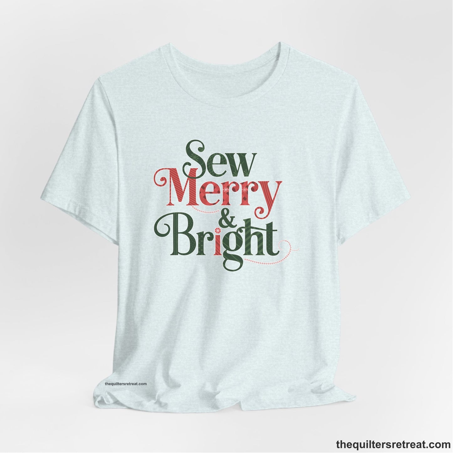 A Heather Ice Blue Short Sleeve T-Shirt with a festive "Sew Merry & Bright" text with decorative holiday patterns