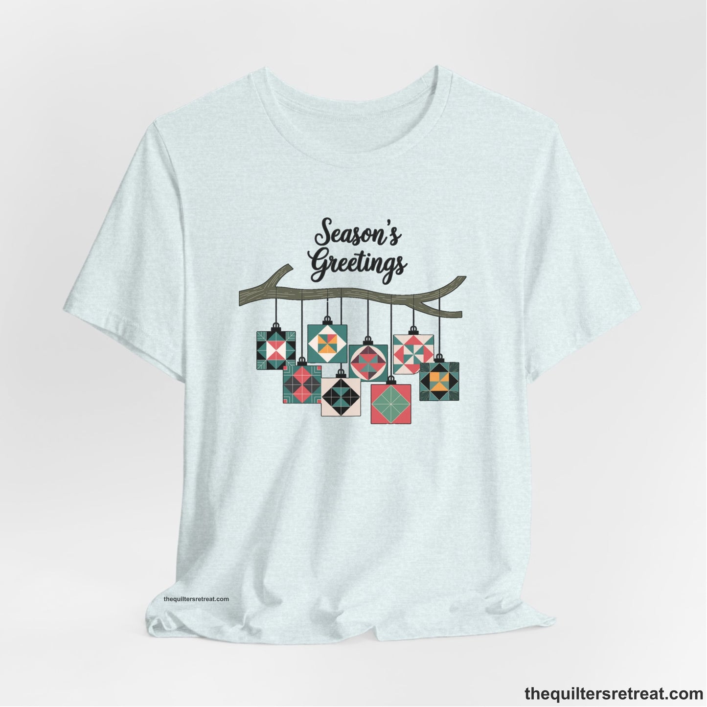 A Heather Ice Blue Short Sleeve T-Shirt with a season's greetings text above colorful quilt block ornaments on tree branch in rustic style