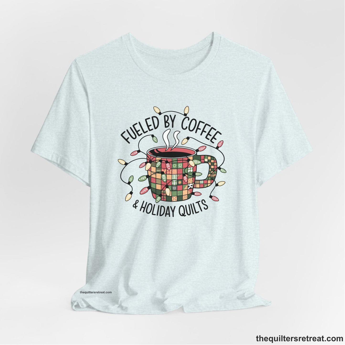A Heather Ice Blue Short Sleeve T-Shirt with a patchwork coffee mug with colorful lights and subtle "Fueled by Coffee" text in festive style