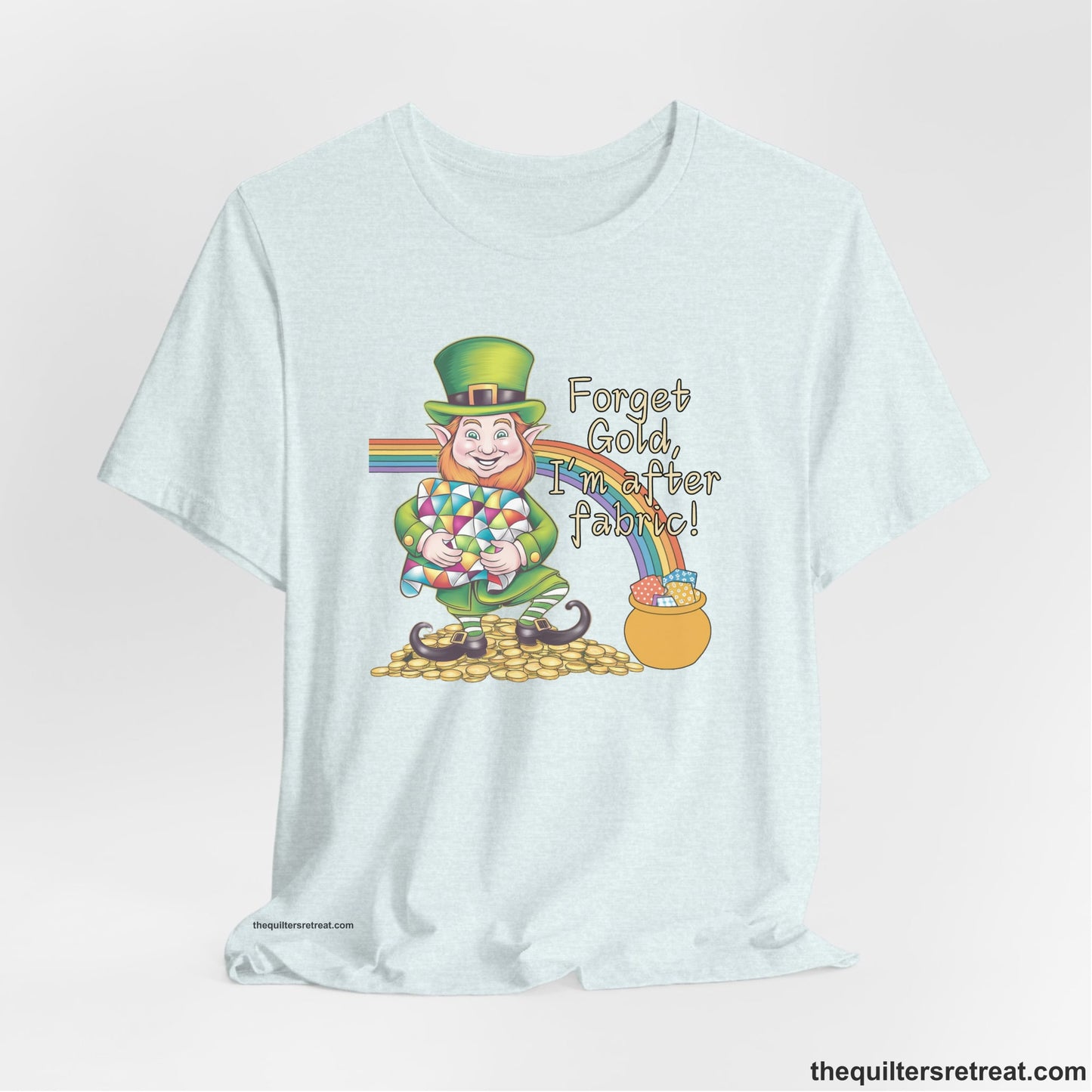 A Heather Ice Blue Short Sleeve T-Shirt with a leprechaun with colorful quilt and rainbow, whimsical "Forget Gold, I'm after fabric!" text
