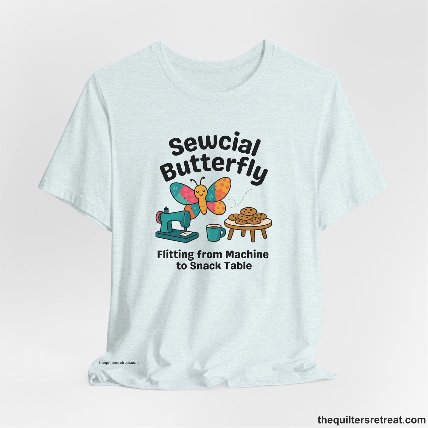 A Heather Ice Blue Short Sleeve T-Shirt with a playful butterfly near sewing machine with cookies and coffee doodle design
