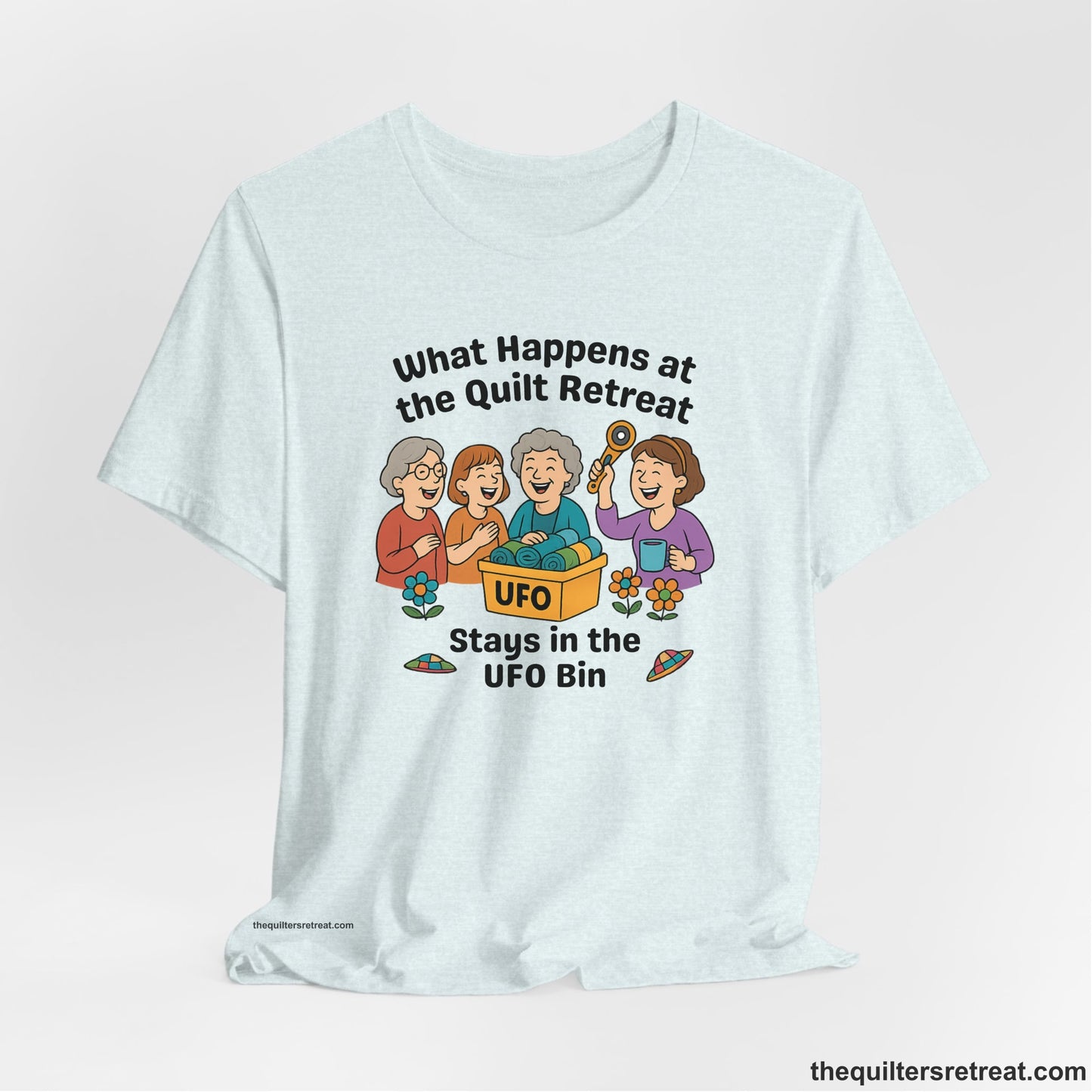 A Heather Ice Blue Short Sleeve T-Shirt with a four smiling women with unfinished fabric objects and playful "UFO" text in a cartoon style
