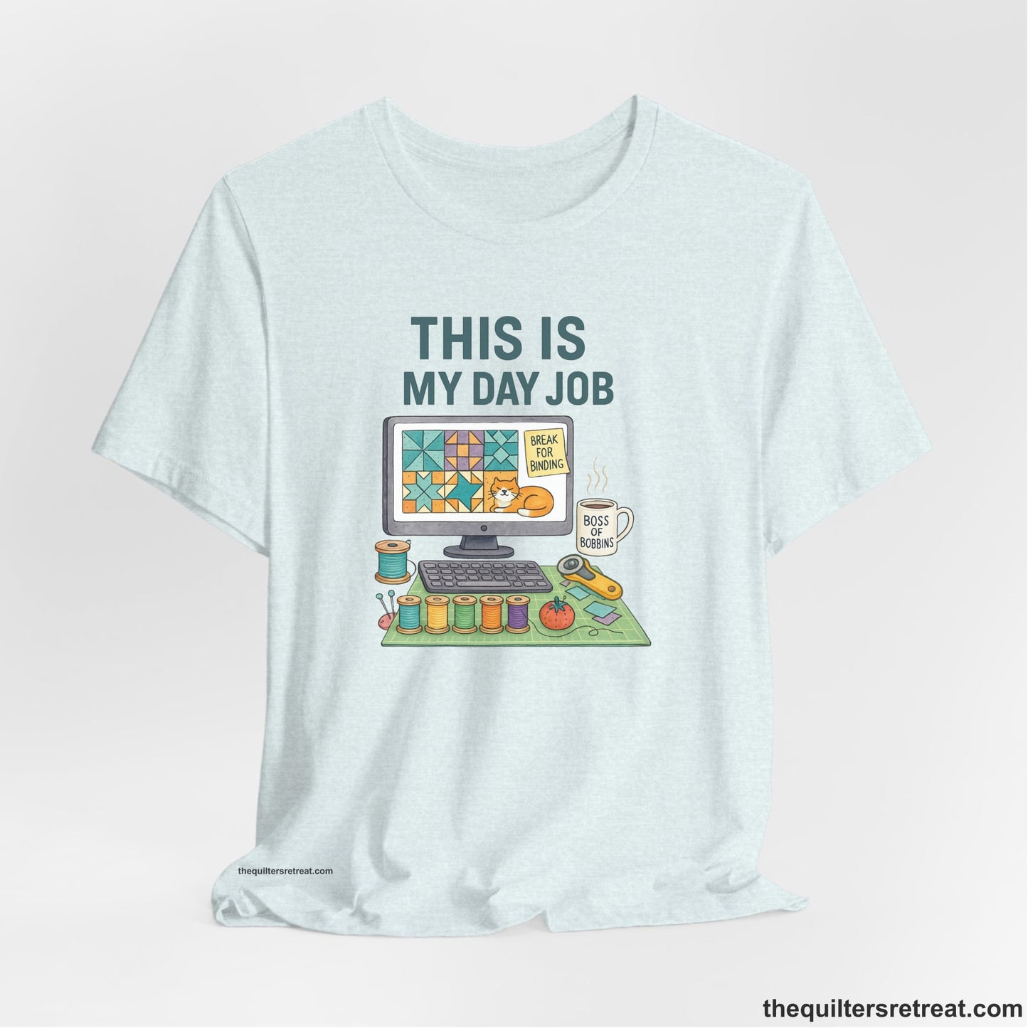 A Heather Ice Blue Short Sleeve T-Shirt with a computer quilt design, cat illustration, "THIS IS MY DAY JOB" text with sewing tools, playful style