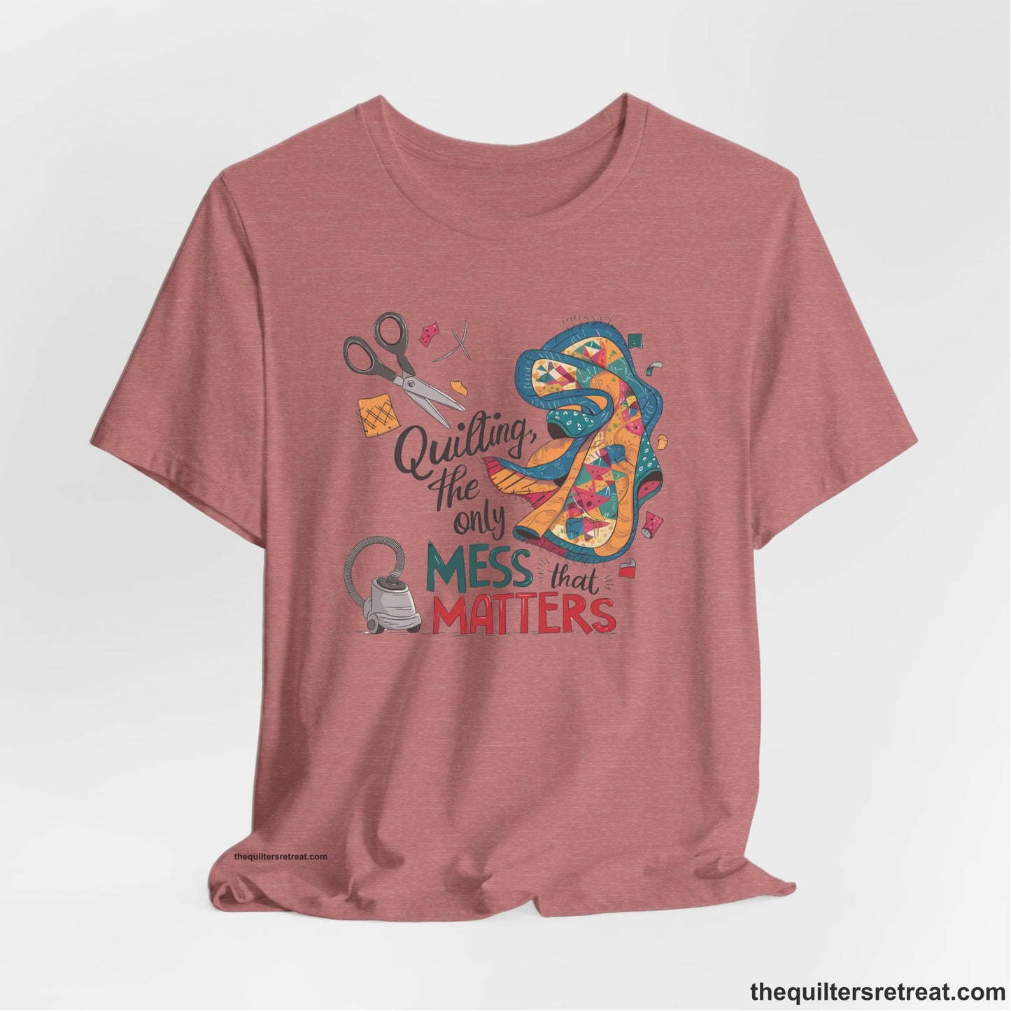 A Heather Mauve Short Sleeve T-Shirt with a quilting tools and patchwork pieces with bold "Quilting, the only mess that matters" text
