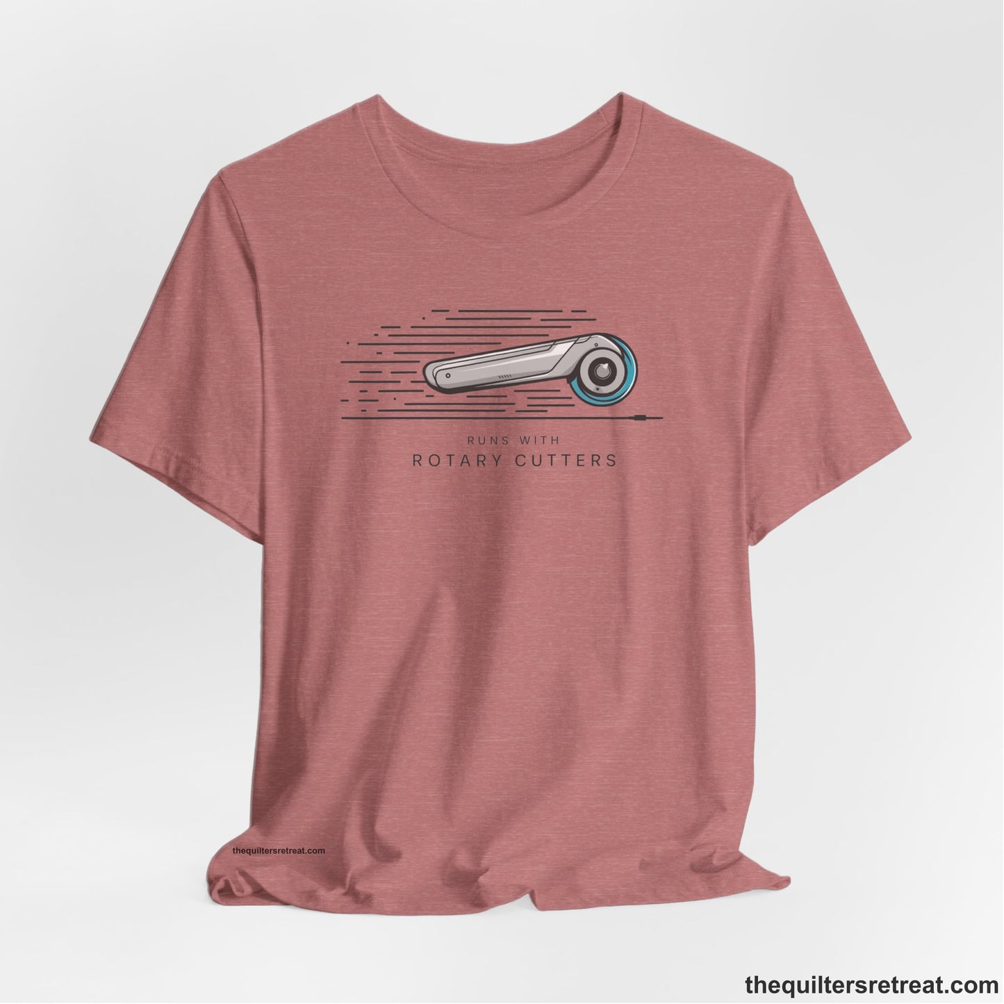 A Heather Mauve Short Sleeve T-Shirt with a rotary cutter illustration with dynamic lines and bold "Runs with Rotary Cutters" text
