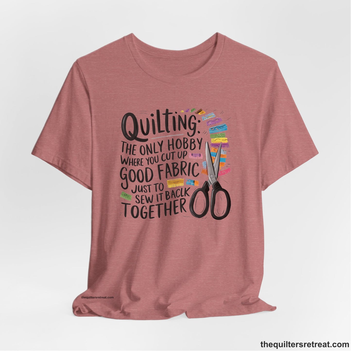 A Heather Mauve Short Sleeve T-Shirt with a quilting-themed text with colorful fabric pieces and scissors in a whimsical style