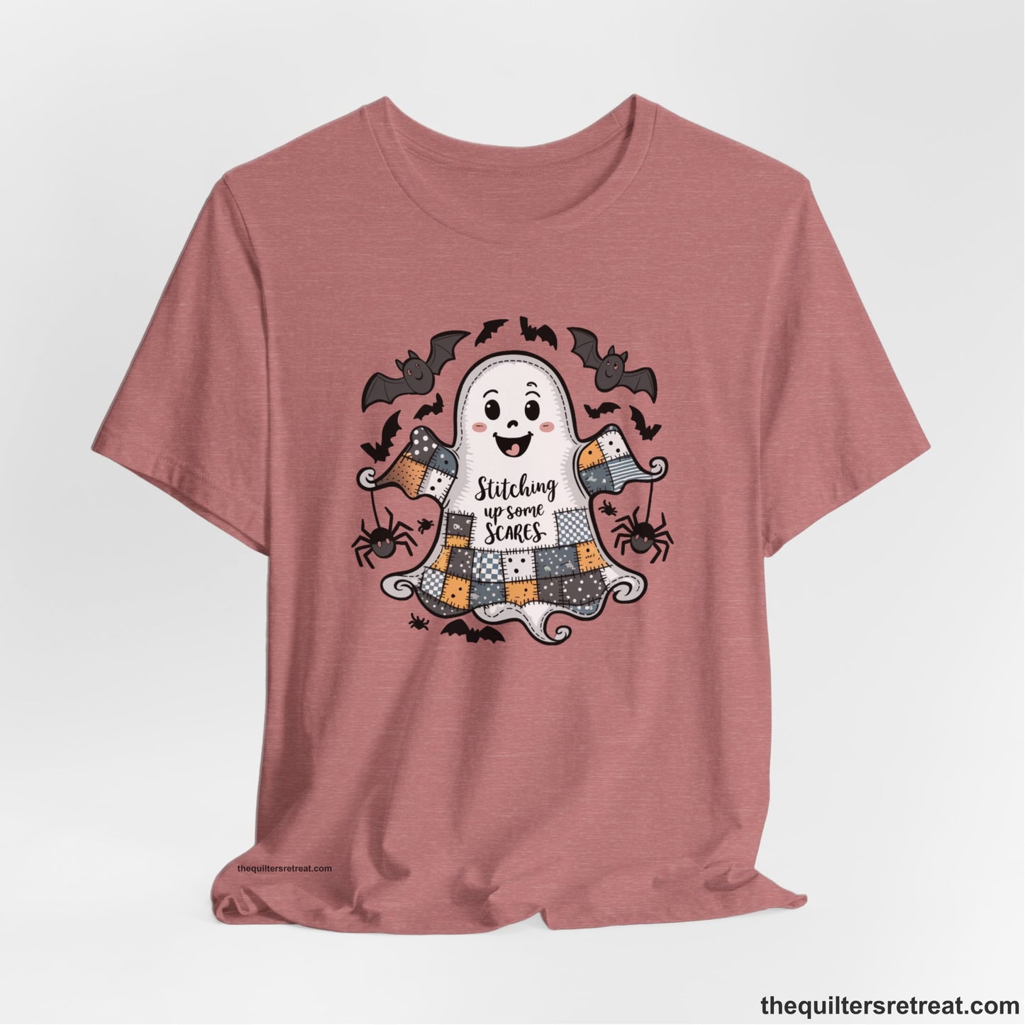 A Heather Mauve Short Sleeve T-Shirt with a cute patchwork ghost with "Stitching up some Scares" text and playful bats in a whimsical style