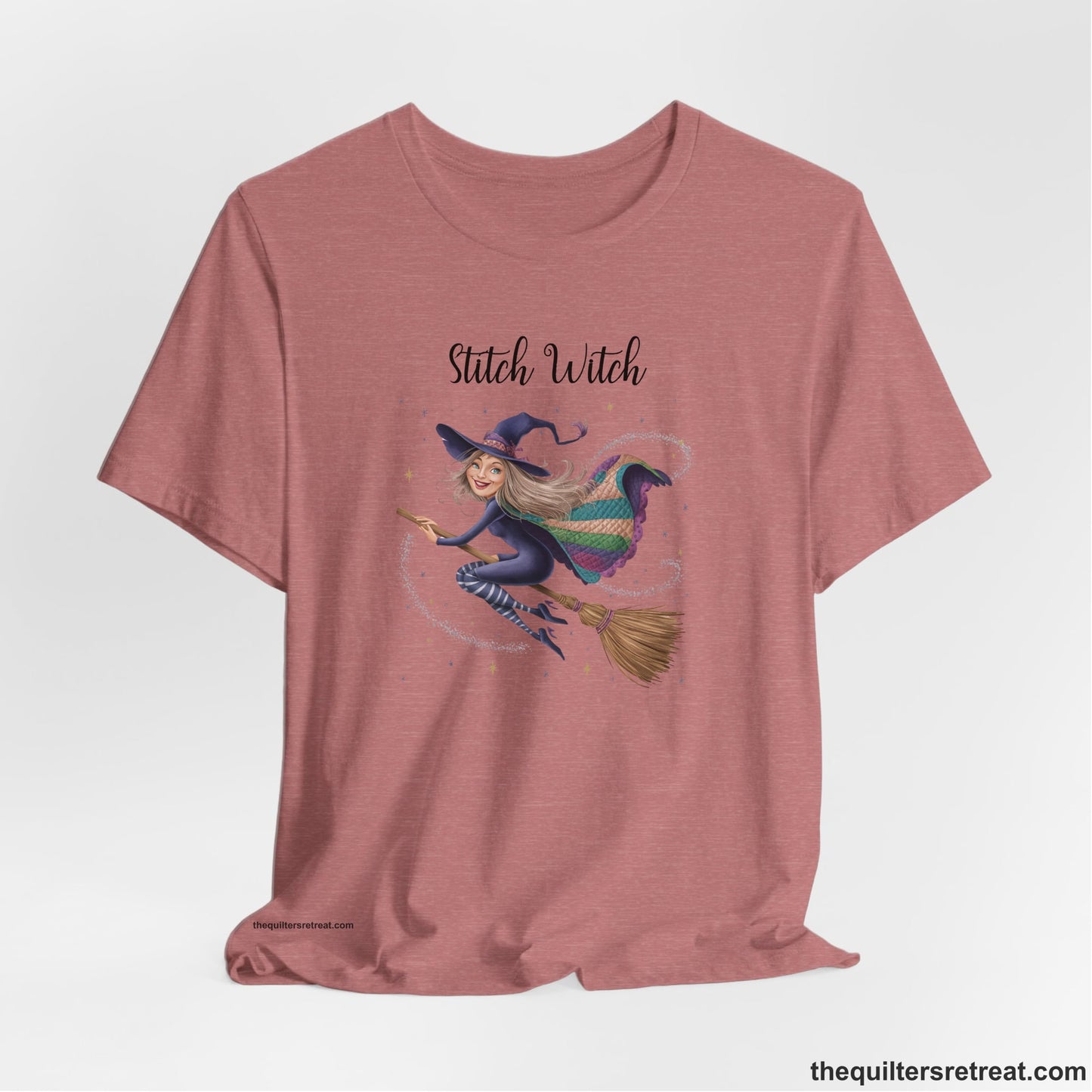 A Heather Mauve Short Sleeve T-Shirt with a playful witch on broomstick with patchwork cape and starry background in a whimsical style