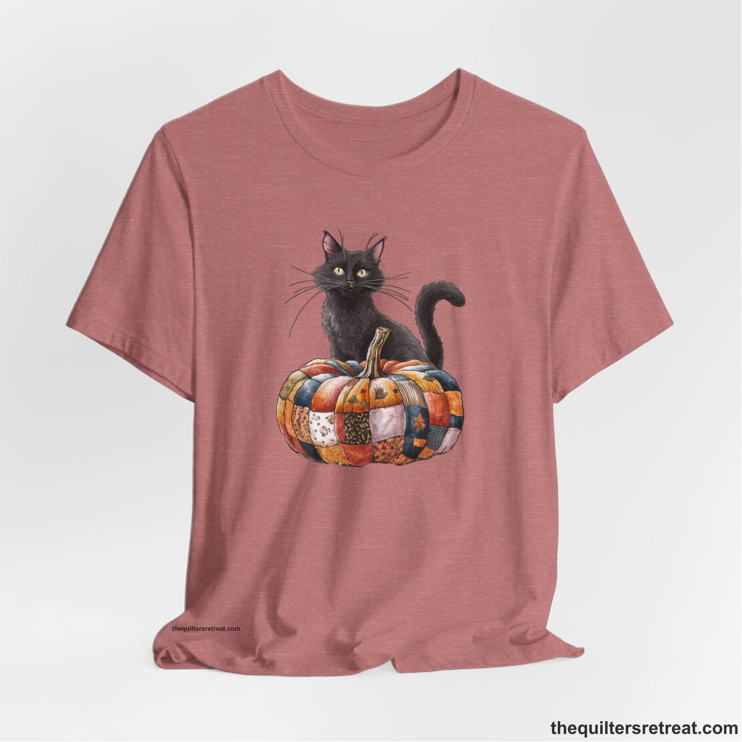 A Heather Mauve Short Sleeve T-Shirt with a black cat with a quilted patchwork pumpkin in a whimsical autumn style