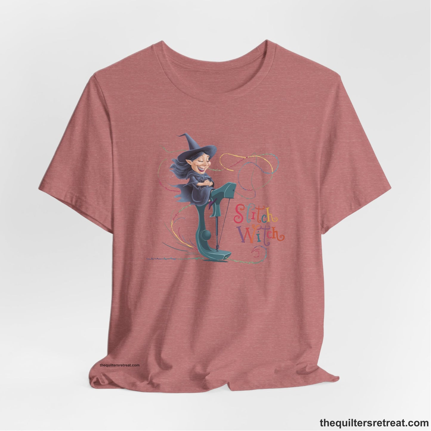 A Heather Mauve Short Sleeve T-Shirt with a witch on vintage sewing machine with "Stitch Witch" text in playful, colorful style