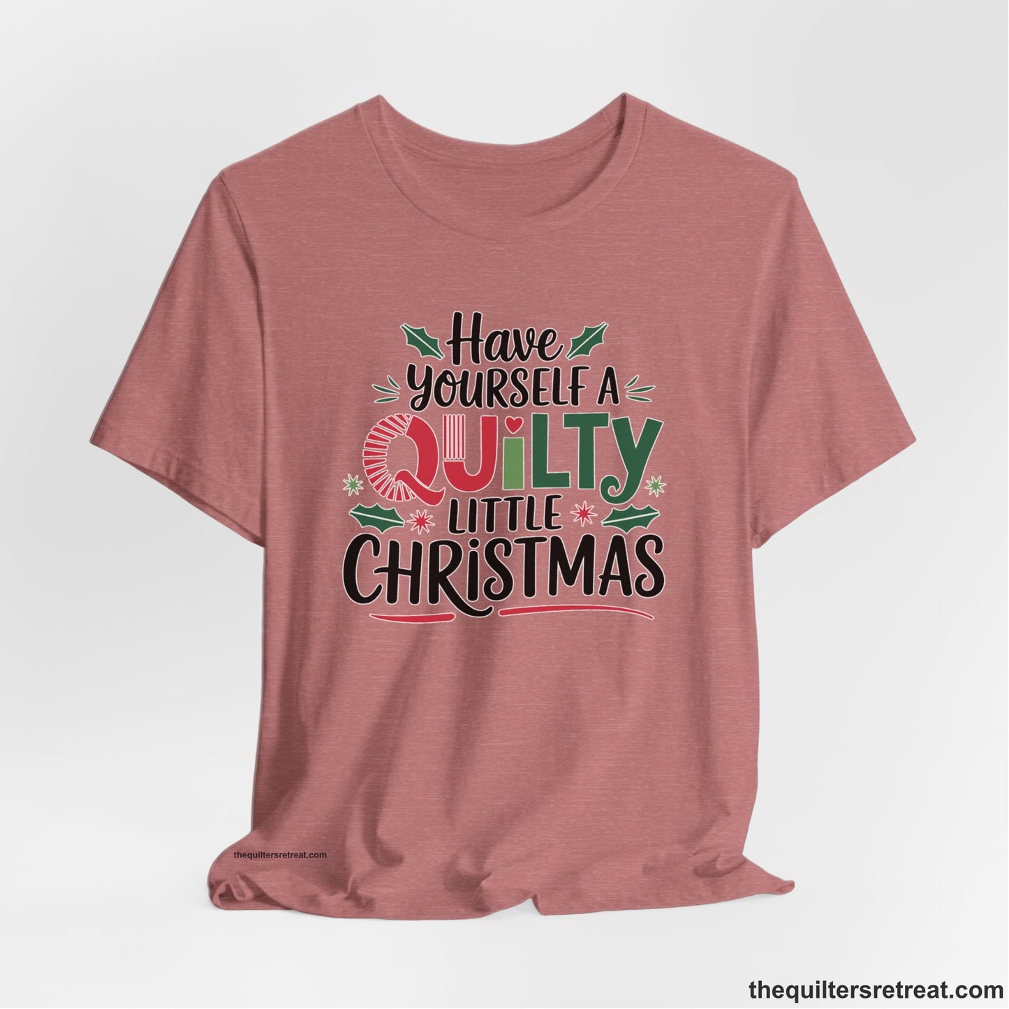 A Heather Mauve Short Sleeve T-Shirt with a festive "Have Yourself a Quilty Little Christmas" text with holly and quilt patterns