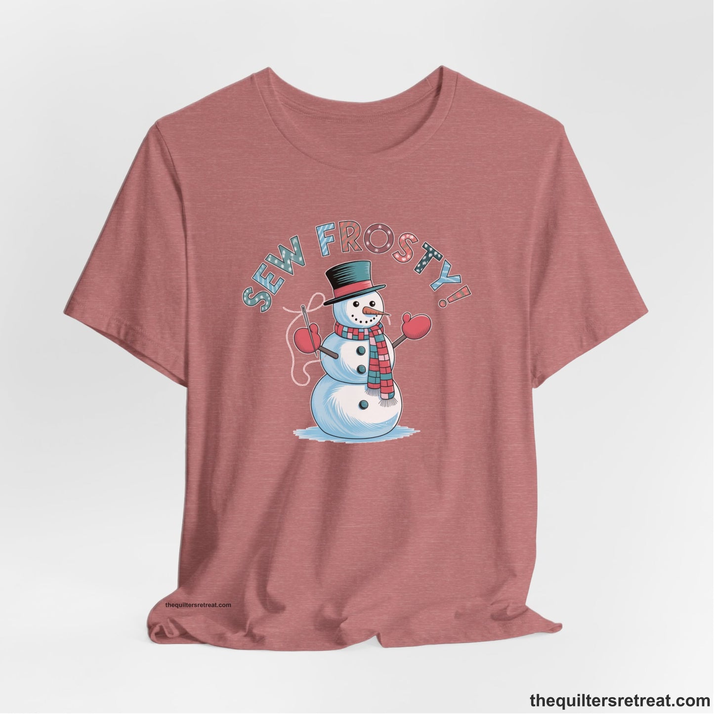 A Heather Mauve Short Sleeve T-Shirt with a playful snowman sewing illustration with "Sew Frosty!" text in a festive style