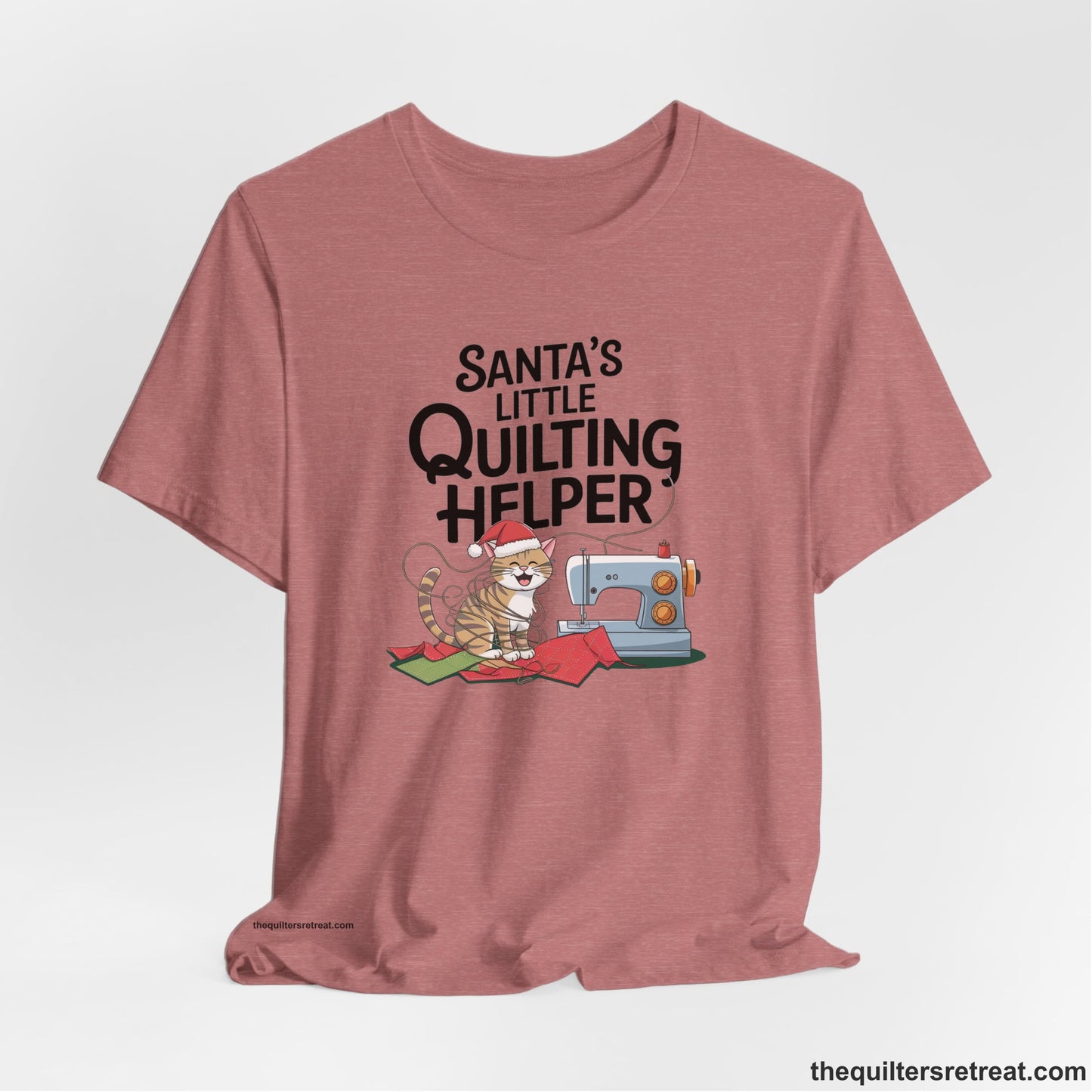 A Heather Mauve Short Sleeve T-Shirt with a santa-hat-wearing kitten with a sewing machine and "Santa's Little Quilting Helper" text in playful style