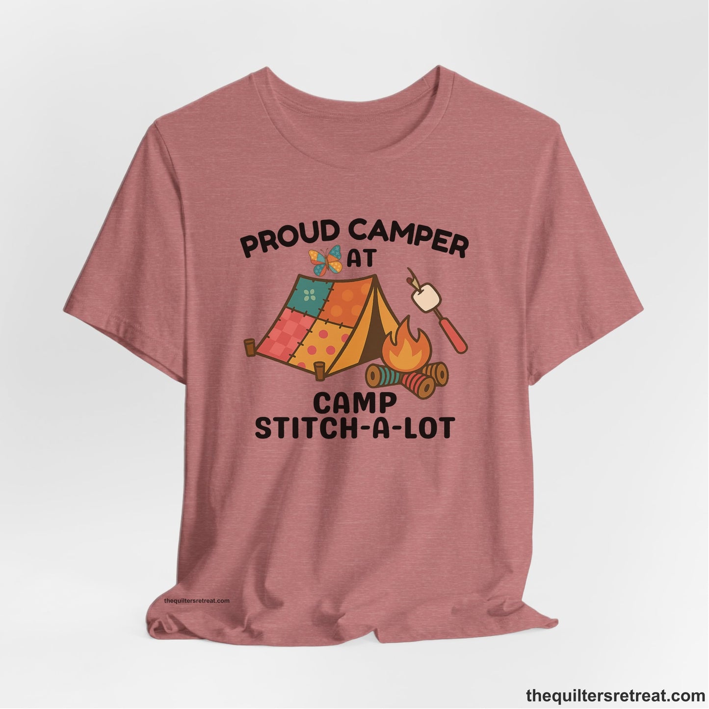 A Heather Mauve Short Sleeve T-Shirt with a camping scene with patchwork tent, campfire, and whimsical butterfly and marshmallow illustration