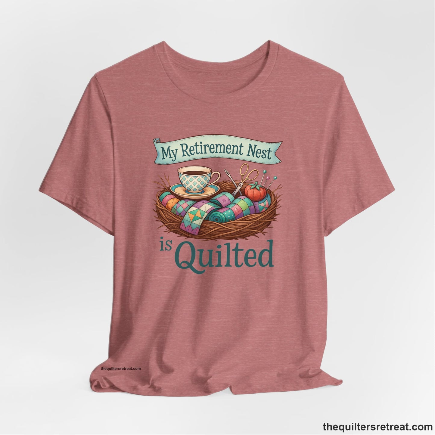 A Heather Mauve Short Sleeve T-Shirt with a My Retirement Nest is Quilted text with a cozy sewing elements illustration