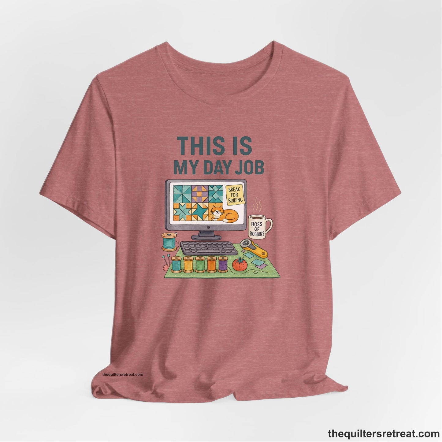 A Heather Mauve Short Sleeve T-Shirt with a computer quilt design, cat illustration, "THIS IS MY DAY JOB" text with sewing tools, playful style