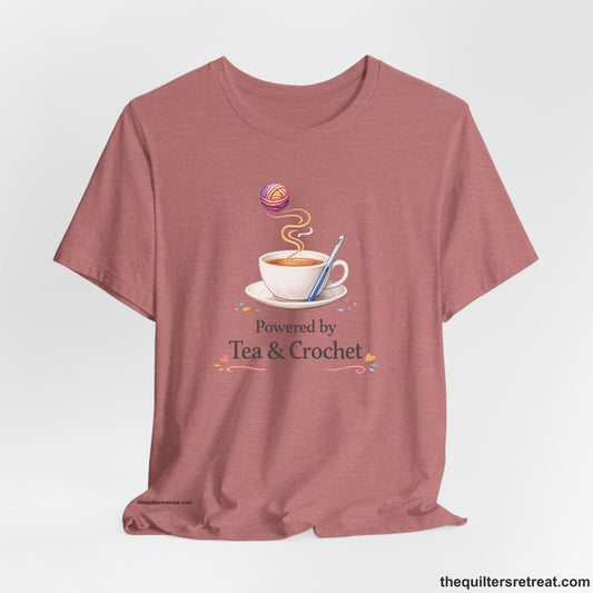 Crochet Gift: A Heather Mauve Short Sleeve T-Shirt with Cup of tea with yarn and crochet hook, playful and cozy, "Powered by Tea & Crochet".