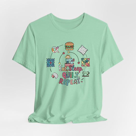 A Heather Mint Short Sleeve T-Shirt with a cute quilting elements with "Eat, Sleep, Quilt, Repeat" text in playful style