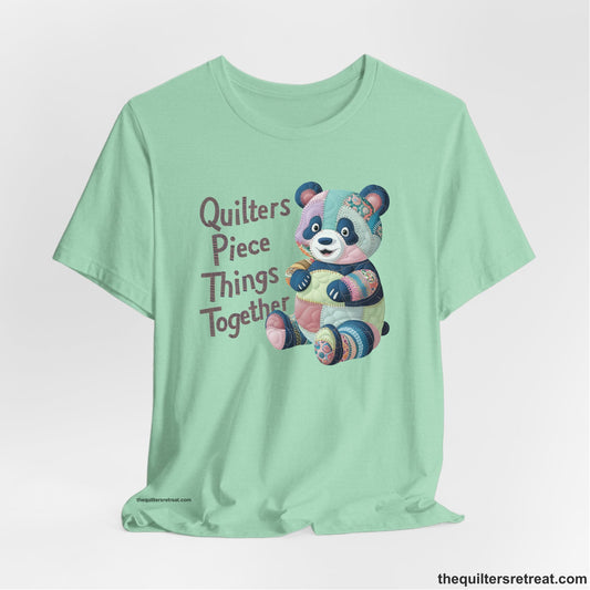 A Heather Mint Short Sleeve T-Shirt with a patchwork panda with "Quilters Piece Things Together" text in a whimsical style