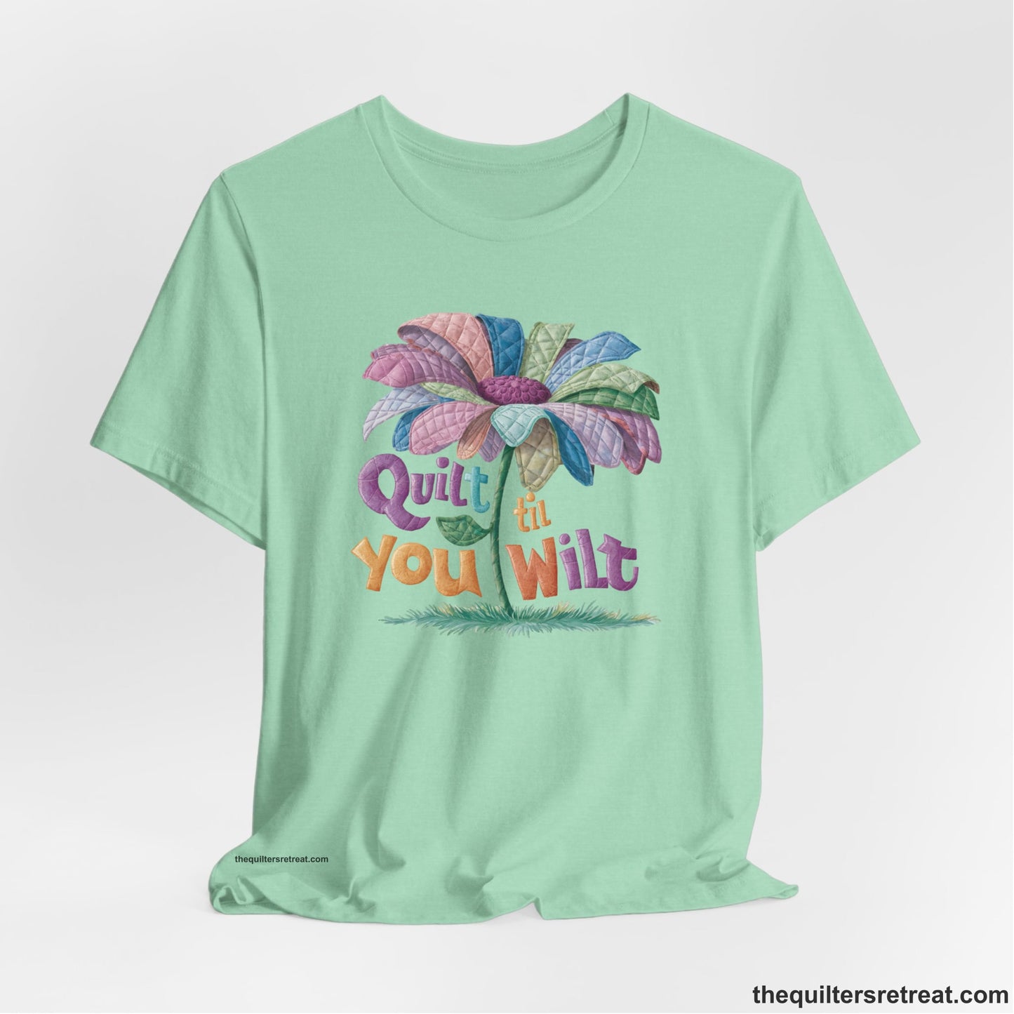 A Heather Mint Short Sleeve T-Shirt with a whimsical quilted flower with bold "Quilt til You Wilt" text
