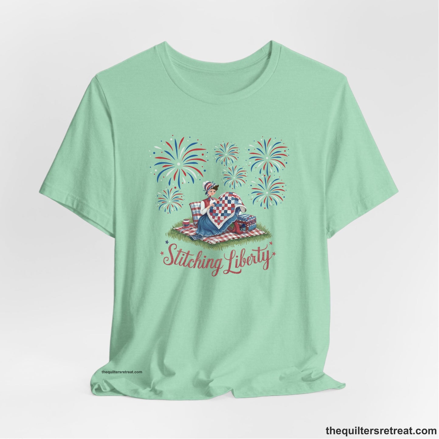 A Heather Mint Short Sleeve T-Shirt with a vintage illustration of woman quilting with fireworks and "Stitching Liberty" text in patriotic style
