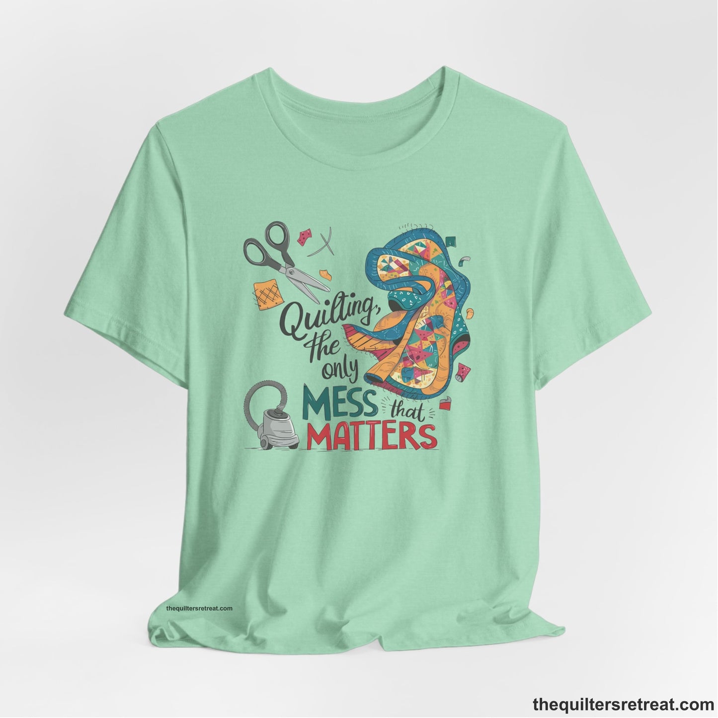 A Heather Mint Short Sleeve T-Shirt with a quilting tools and patchwork pieces with bold "Quilting, the only mess that matters" text