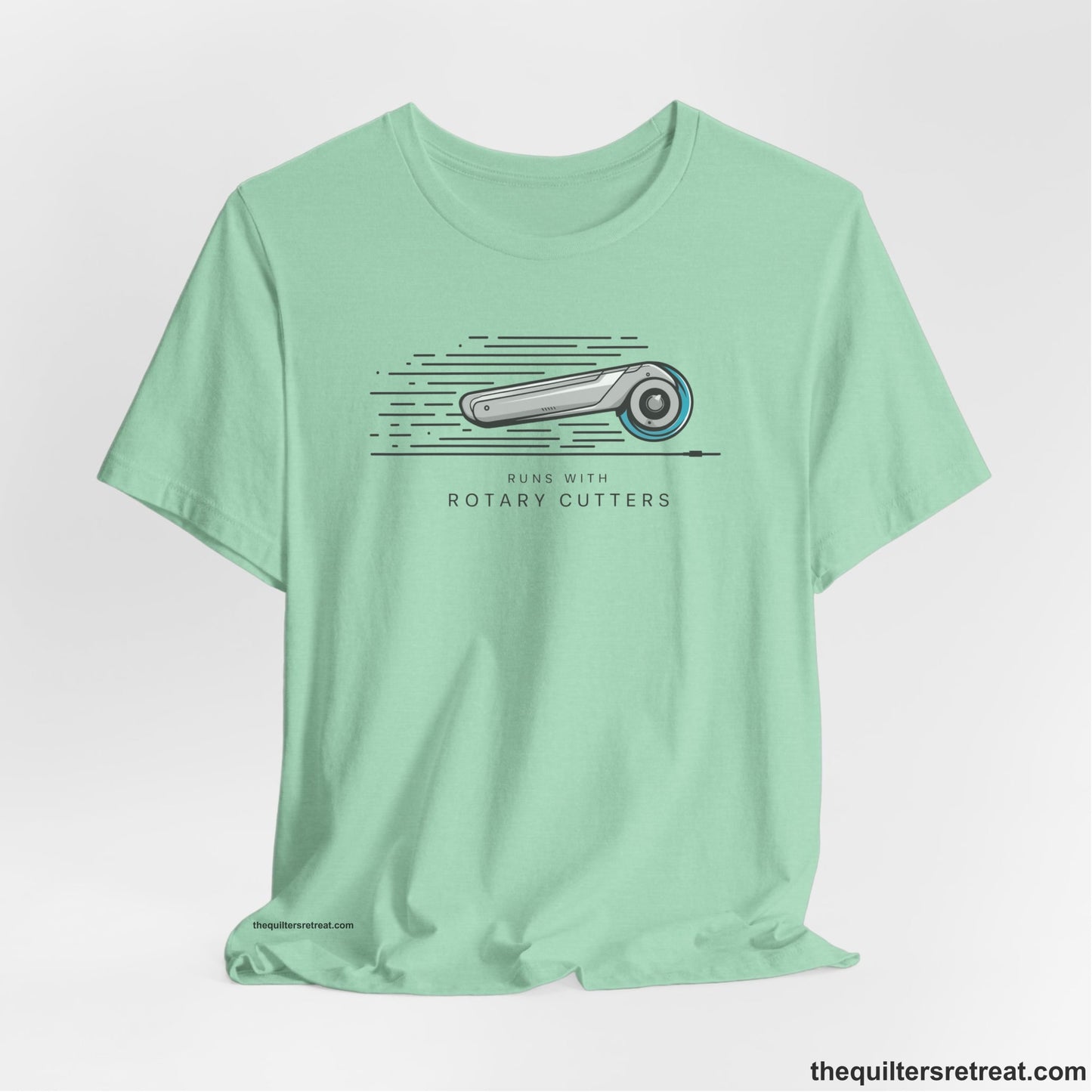 A Heather Mint Short Sleeve T-Shirt with a rotary cutter illustration with dynamic lines and bold "Runs with Rotary Cutters" text