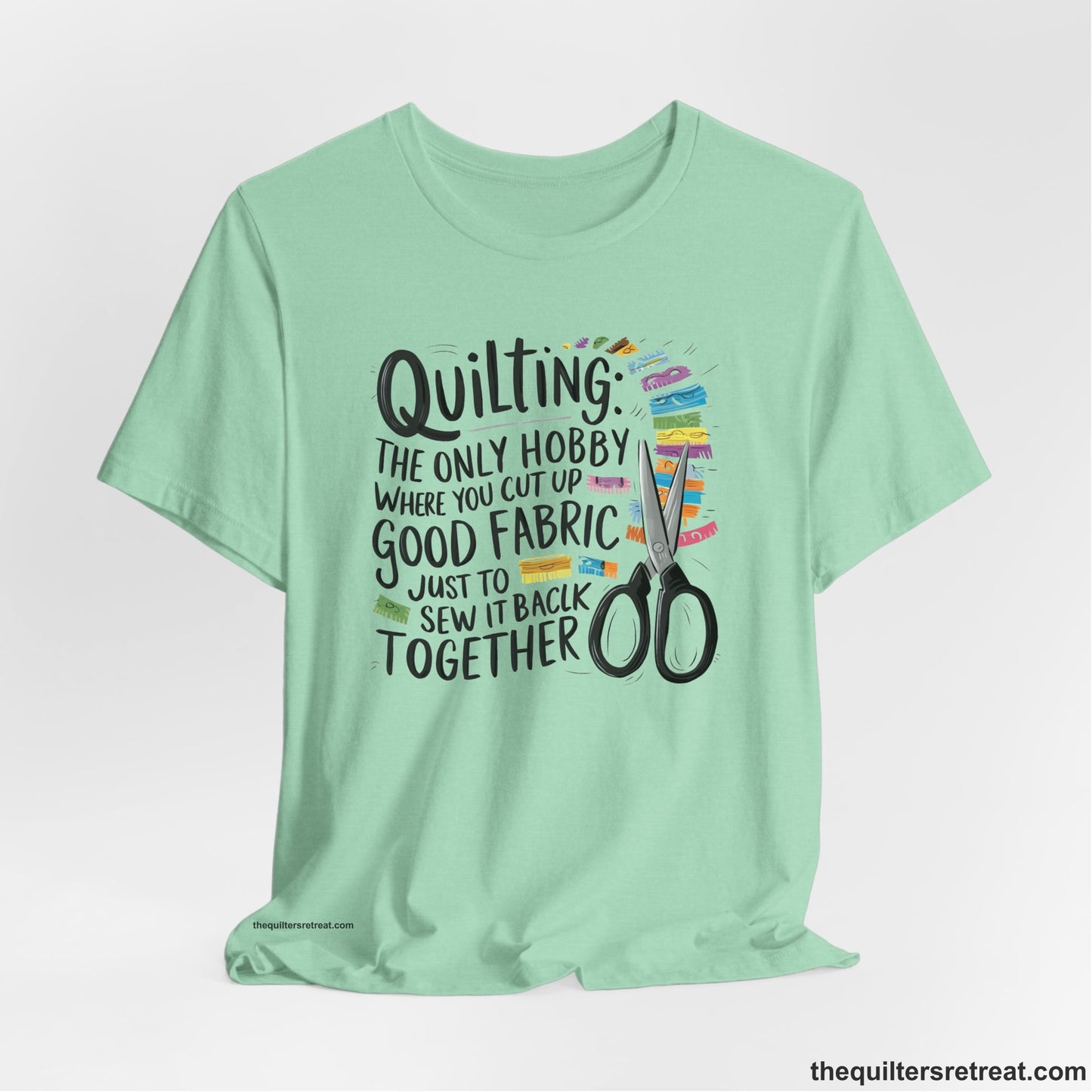 A Heather Mint Short Sleeve T-Shirt with a quilting-themed text with colorful fabric pieces and scissors in a whimsical style