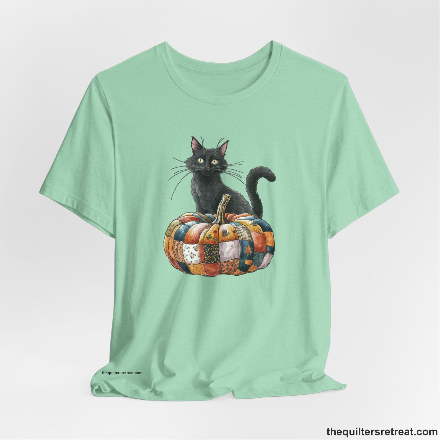 A Heather Mint Short Sleeve T-Shirt with a black cat with a quilted patchwork pumpkin in a whimsical autumn style