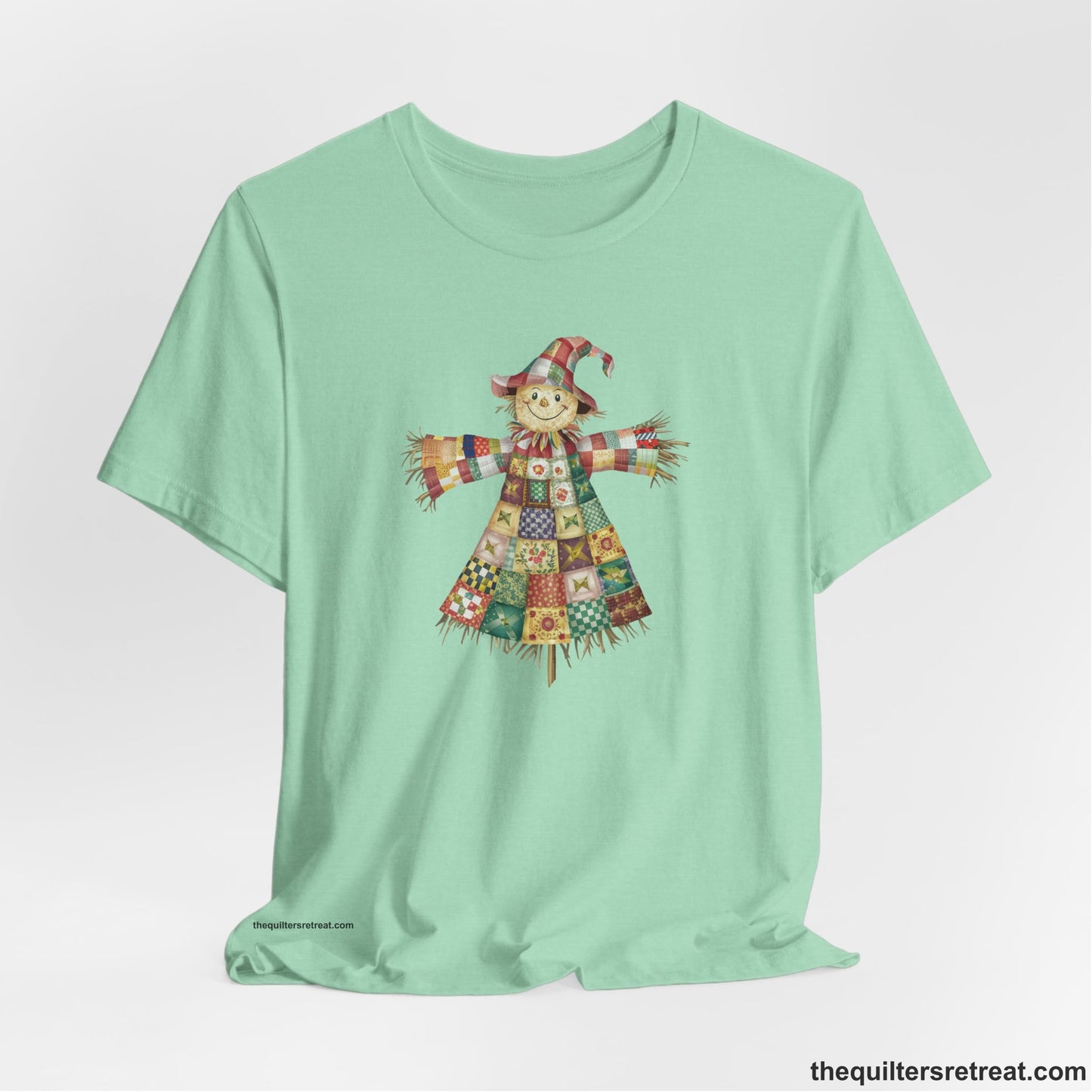 A Heather Mint Short Sleeve T-Shirt with a patchwork scarecrow with a cheerful face in a whimsical style