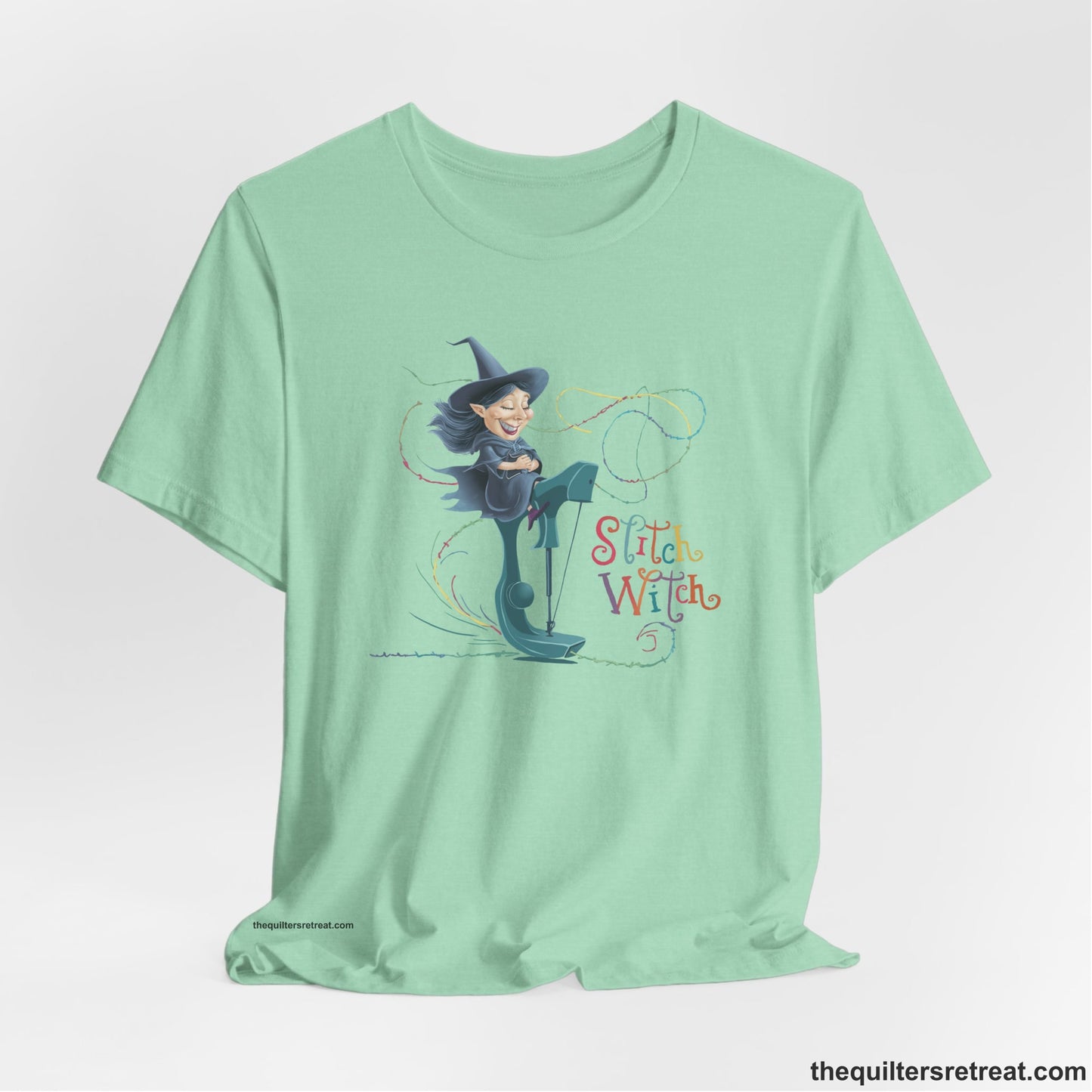 A Heather Mint Short Sleeve T-Shirt with a witch on vintage sewing machine with "Stitch Witch" text in playful, colorful style