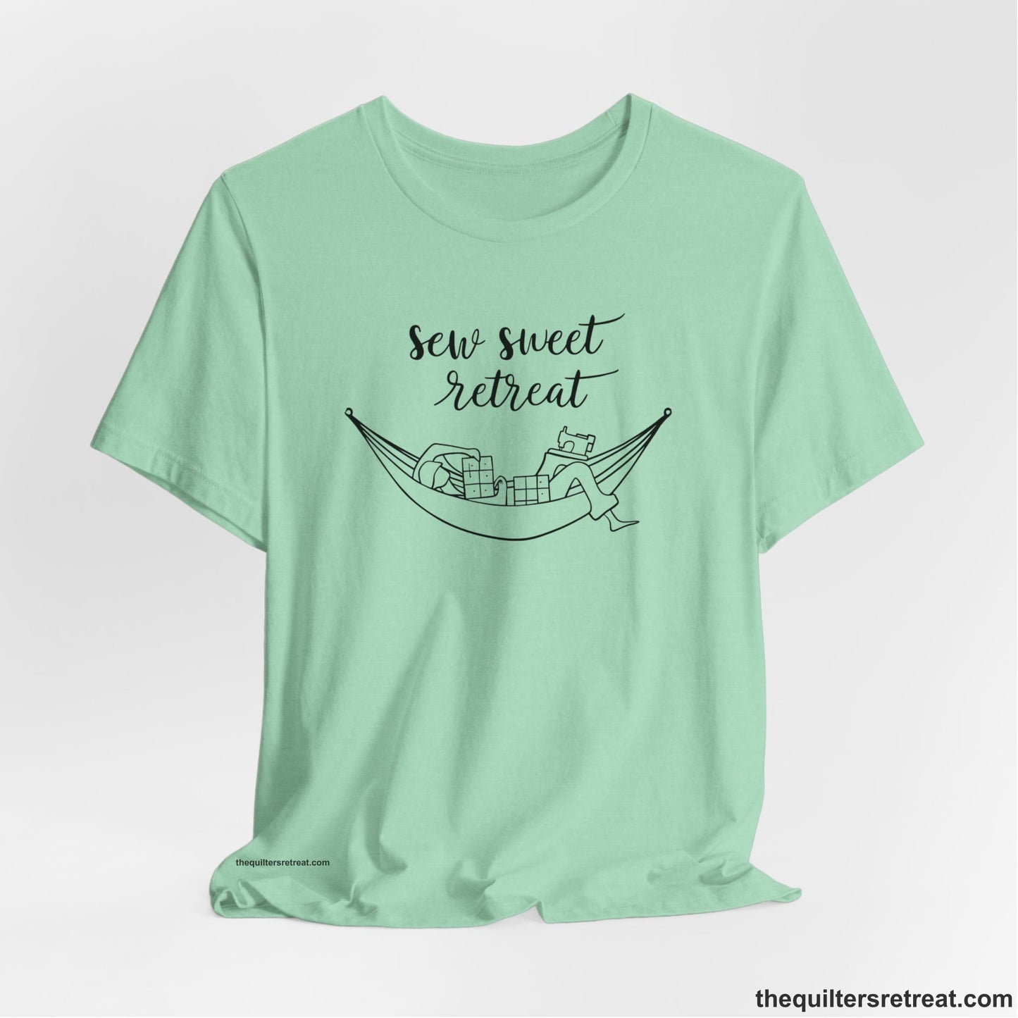 A Heather Mint Short Sleeve T-Shirt with a sewing machine and thread spools with "Sew Sweet Retreat" in whimsical script
