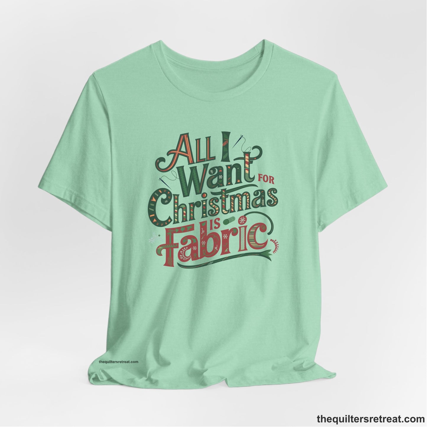A Heather Mint Short Sleeve T-Shirt with a vintage holiday text "All I Want for Christmas is Fabric" with festive motifs
