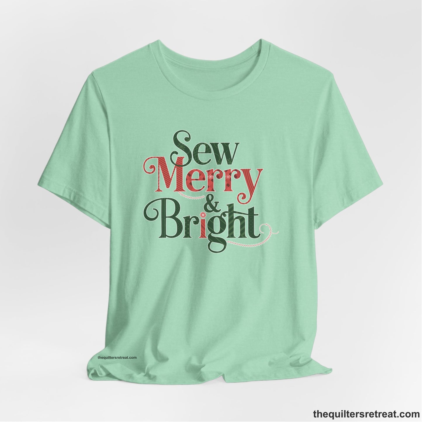 A Heather Mint Short Sleeve T-Shirt with a festive "Sew Merry & Bright" text with decorative holiday patterns