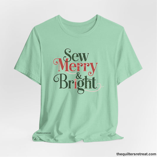 A Heather Mint Short Sleeve T-Shirt with a festive "Sew Merry & Bright" text with decorative holiday patterns