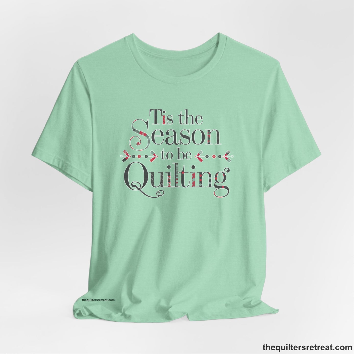 A Heather Mint Short Sleeve T-Shirt with a tis the season to be quilting text with festive patchwork pattern in a cheerful style