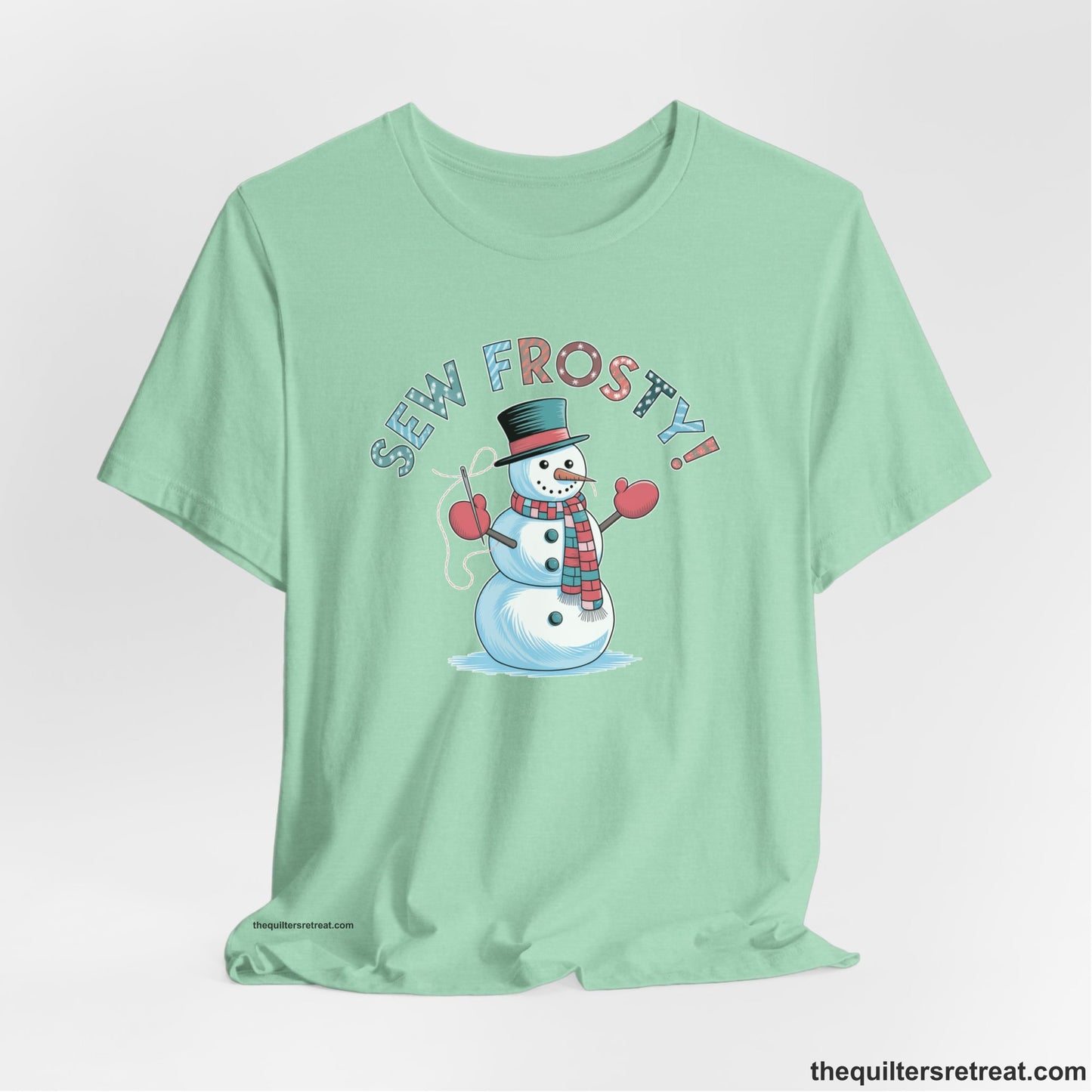 A Heather Mint Short Sleeve T-Shirt with a playful snowman sewing illustration with "Sew Frosty!" text in a festive style