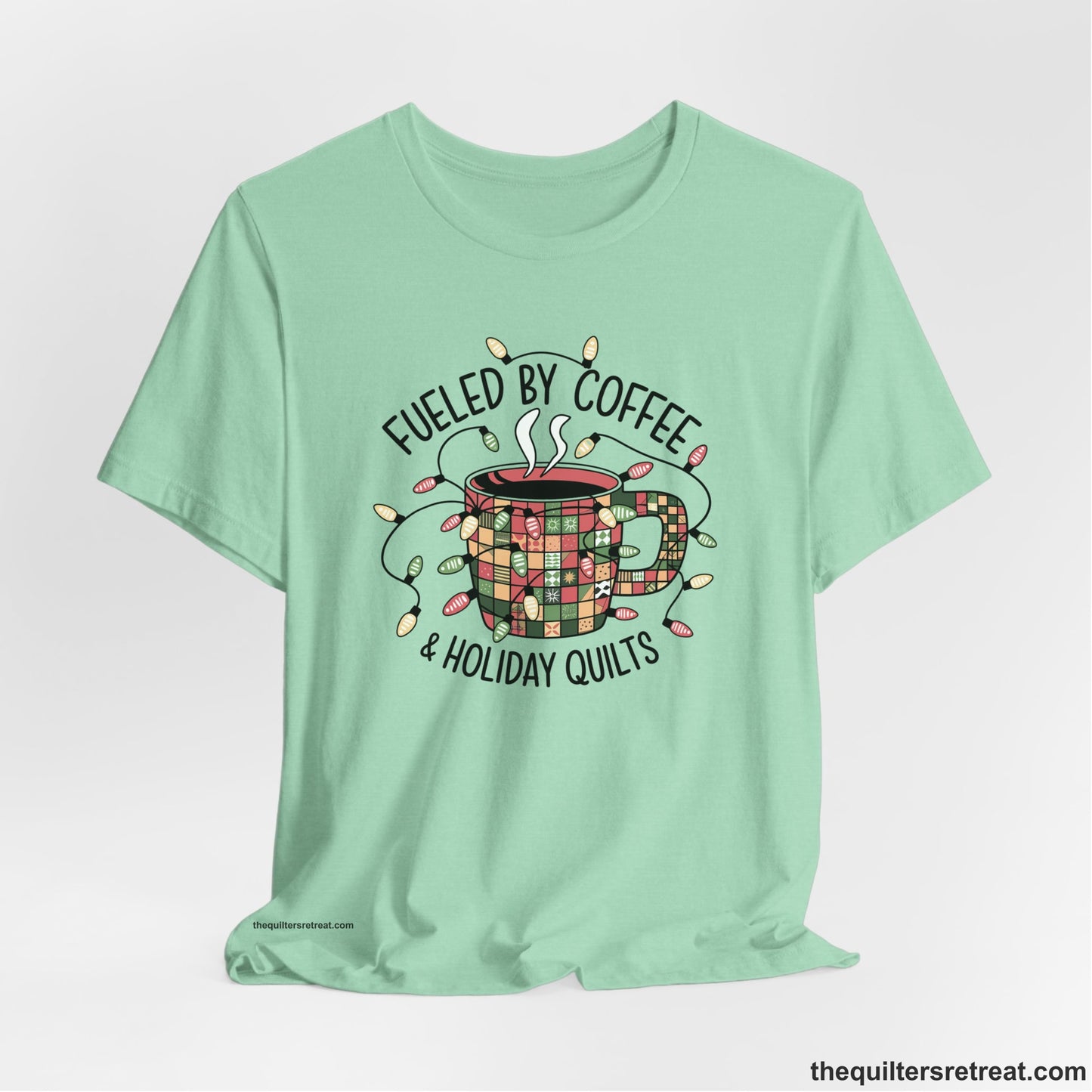 A Heather Mint Short Sleeve T-Shirt with a patchwork coffee mug with colorful lights and subtle "Fueled by Coffee" text in festive style
