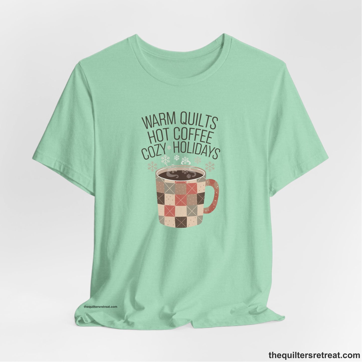 A Heather Mint Short Sleeve T-Shirt with a warm quilts hot coffee cozy holidays text with a patchwork mug and snowflakes
