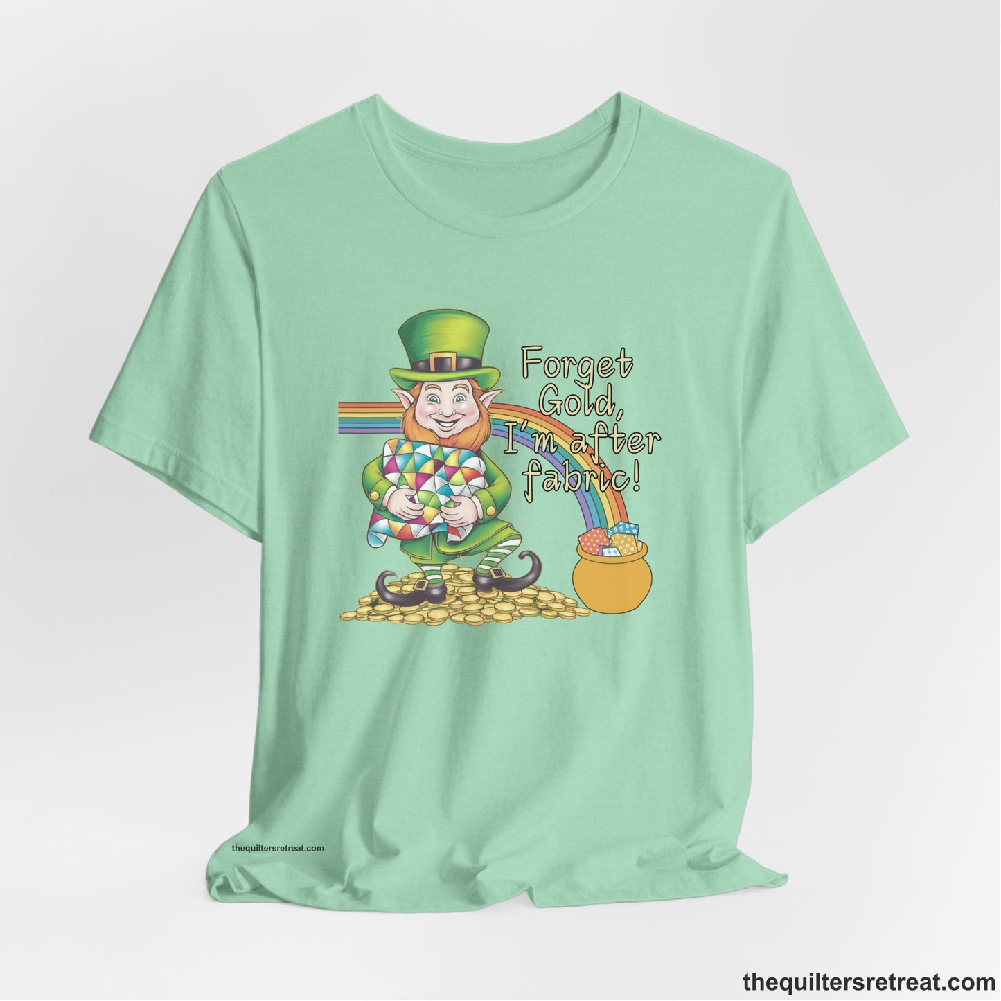 A Heather Mint Short Sleeve T-Shirt with a leprechaun with colorful quilt and rainbow, whimsical "Forget Gold, I'm after fabric!" text