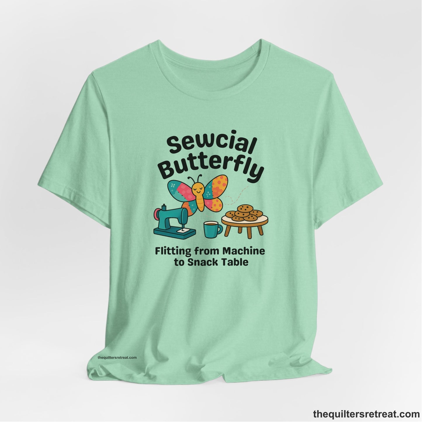 A Heather Mint Short Sleeve T-Shirt with a playful butterfly near sewing machine with cookies and coffee doodle design