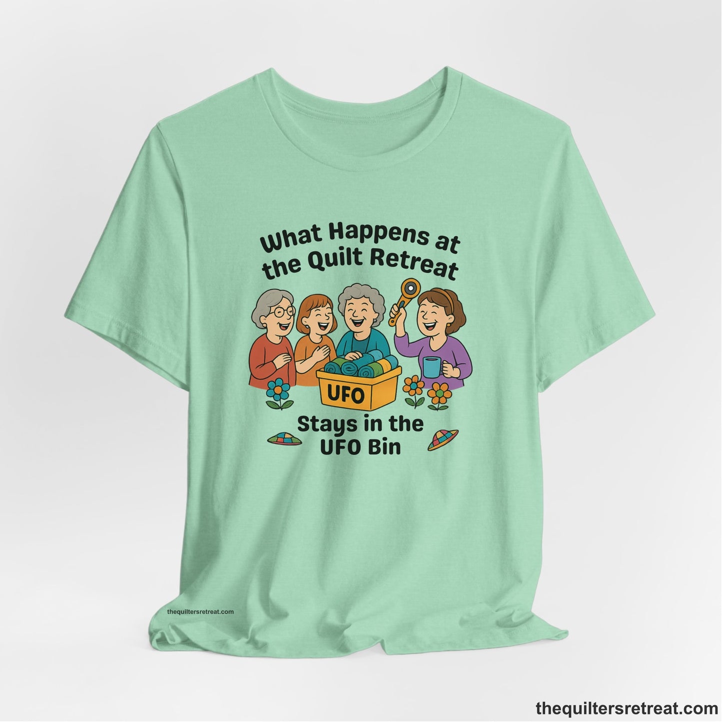 A Heather Mint Short Sleeve T-Shirt with a four smiling women with unfinished fabric objects and playful "UFO" text in a cartoon style